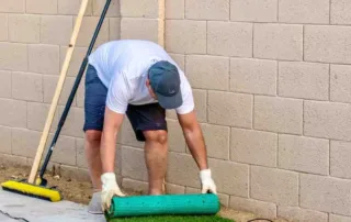 How to Install Synthetic Turf Grass by rolling out artificial grass over a prepared base during DIY synthetic grass installation